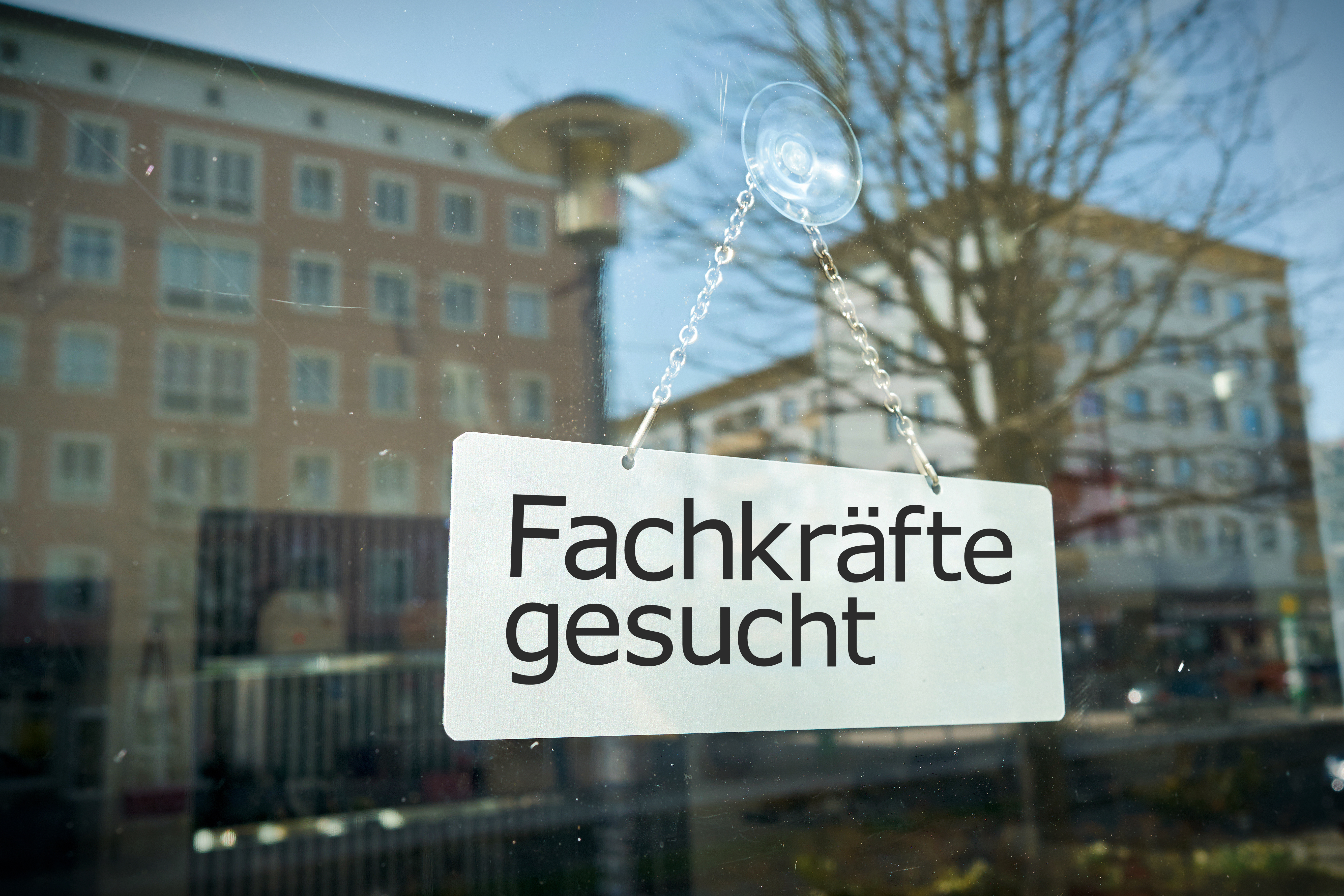 Schild mit Aufschrift "Fachkräfte gesucht" an Schaufensterscheibe