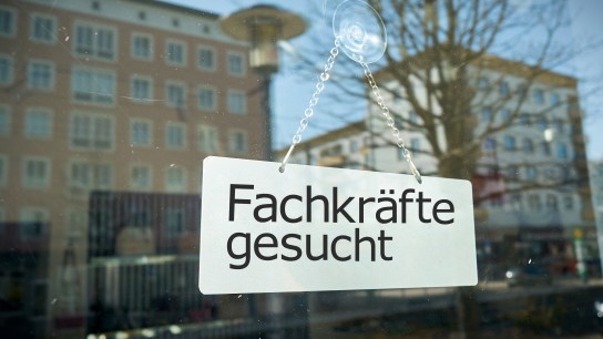 Schild mit Aufschrift "Fachkräfte gesucht" an Schaufensterscheibe